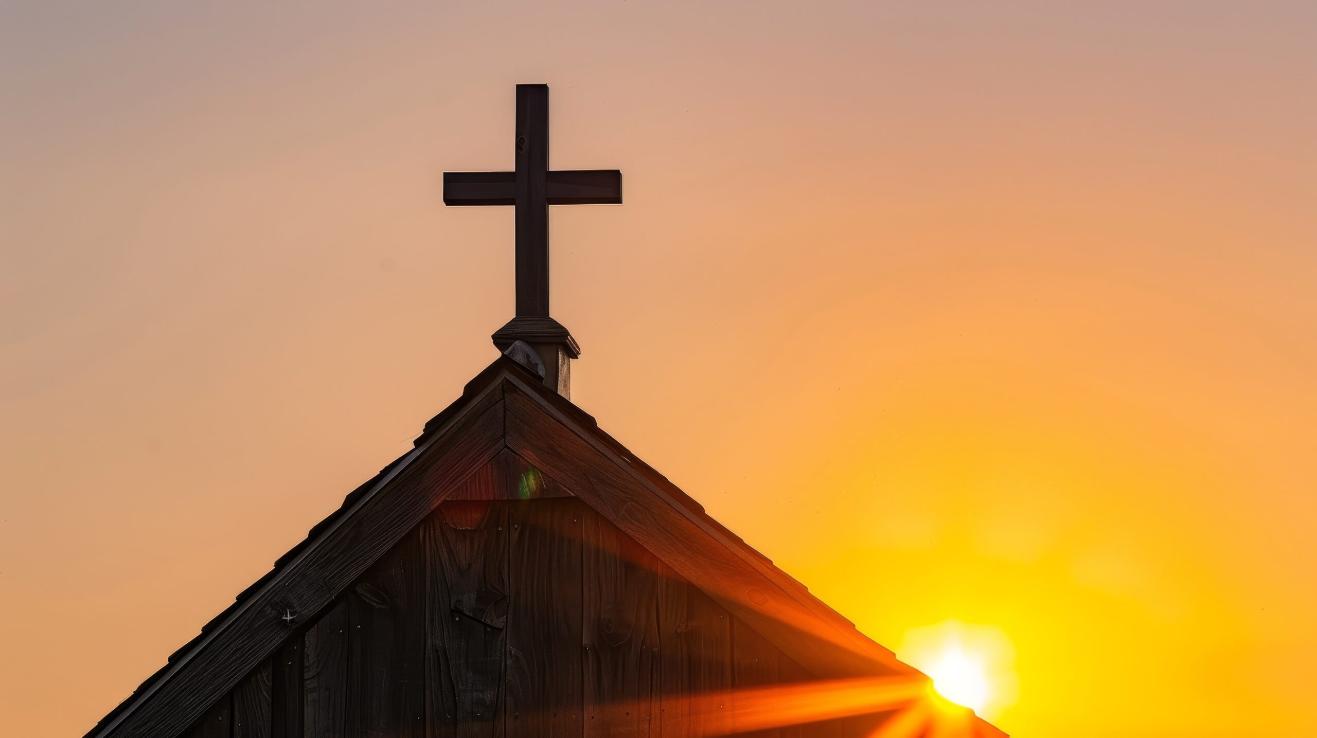 Wooden cross on an old church steeple backlit by the rising sun, symbolizing faith and renewal with ample copy space for inspirational messages